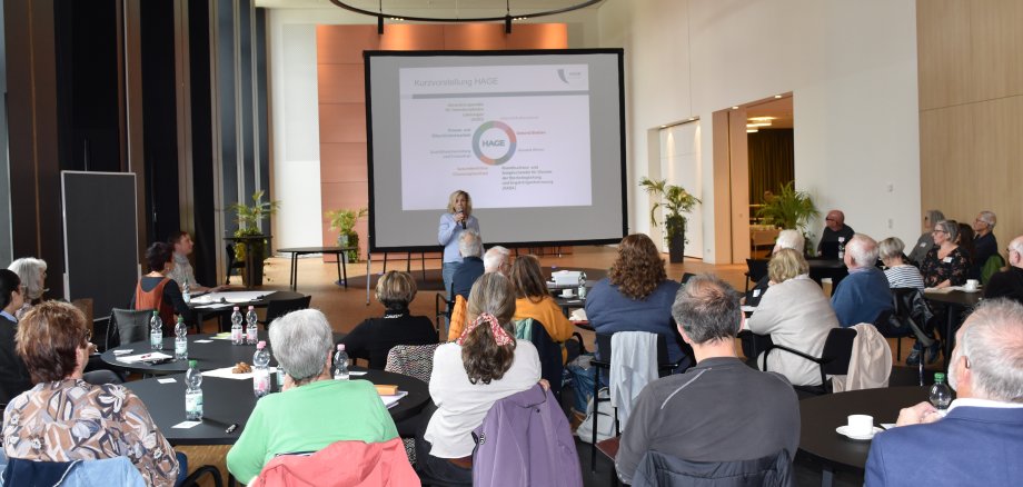 Das Foto zeigt eine Rednerin und eine Gruppe von Teilnehmern beim Treffen der Nachbarschafts- und Generationenhilfen in Erbach.